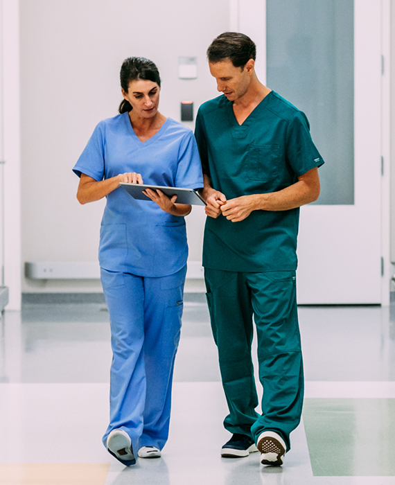 Nurse and doctor consulting tablet device in hospital corridor