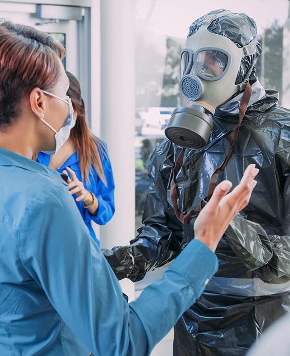 Public health official in hazmat suit screens female wearing protective face mask during infectious disease outbreak