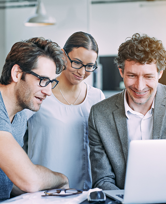 Three software developers working on JavaScript code on large computer monitor in modern office setting