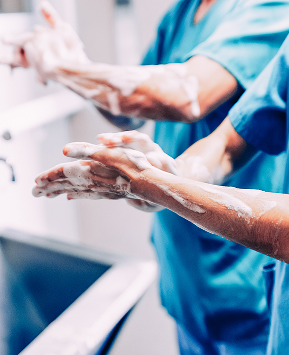 Two surgeons washing hands and arms in front of steel sink before operating